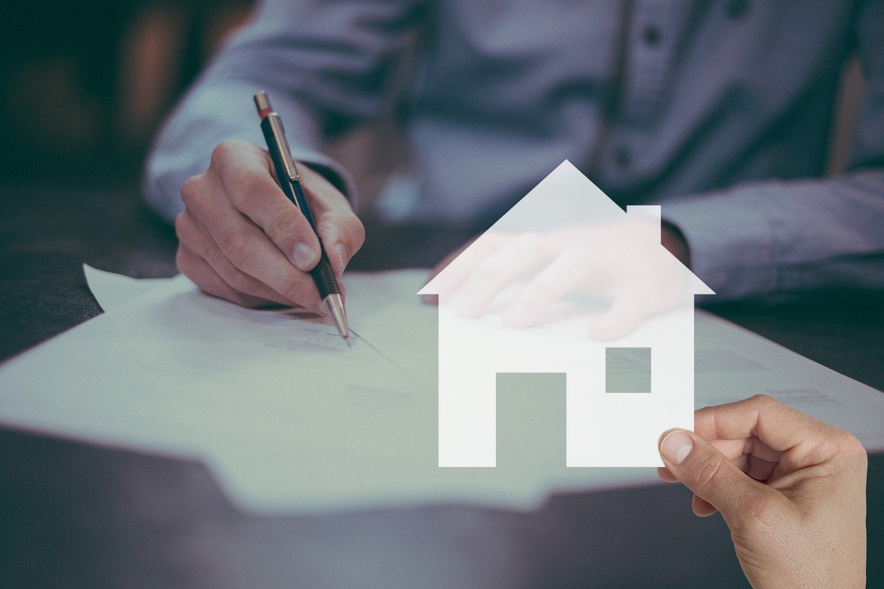 En selger som signerer på en boligselgerforsikring etter salg av bolig